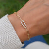 Woman wearing a 14k gold Adelaide paperclip chain pavé bracelet featuring one aquamarine-encrusted link