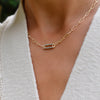 Woman wearing a 14k yellow gold Adelaide paperclip chain necklace featuring one link encrusted with 1.5 mm pavé alexandrites
