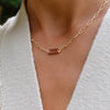 Woman wearing a 14k yellow gold Adelaide paperclip chain necklace featuring one link encrusted with 1.5 mm pavé garnets