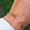 Woman wearing a 14k yellow gold Adelaide paperclip chain pavé bracelet featuring garnet-encrusted links