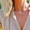 Woman wearing a 14k gold Liberty Newport necklace featuring alternating 4 mm briolette white topaz, sapphires and rubies