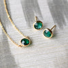 A Grand emerald necklace and a pair of 14k gold Grand stud earrings each featuring one 6 mm briolette cut bezel set emerald