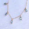 Close-up of a Providence 5 Nantucket Blue Topaz drop necklace with petite baguette cut stones set in 14k yellow gold