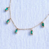 Close-up of a Providence 5 Emerald drop necklace with petite baguette cut stones set in 14k yellow gold