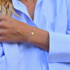 Woman wearing a 14k yellow gold cable chain bracelet featuring one 1/4” flat disc engraved with the letter A