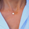 Woman with a 14k yellow gold cable chain necklace featuring one 1/4” flat disc engraved with the letter A