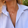 Woman wearing a 14k yellow gold cable chain necklace featuring one 1/4” flat disc engraved with the letter B