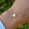 Woman's hand wearing a 14k yellow gold cable chain bracelet featuring one 1/4” flat disc engraved with the letter C
