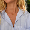 Woman wearing a 14k yellow gold cable chain necklace featuring one 1/4” flat disc engraved with the letter D