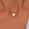 Woman with a 14k yellow gold cable chain necklace featuring one 1/4” flat disc engraved with the letter D