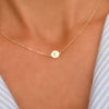 Woman with a 14k yellow gold cable chain necklace featuring one 1/4” flat disc engraved with the letter E