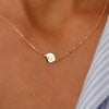 Woman wearing a 14k yellow gold cable chain necklace featuring one 1/4” flat disc engraved with the letter G