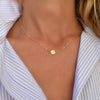 Woman with a 14k yellow gold cable chain necklace featuring one 1/4” flat disc engraved with the letter I