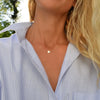 Woman wearing a 14k yellow gold cable chain necklace featuring one 1/4” flat disc engraved with the letter J