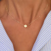 Woman with a 14k yellow gold cable chain necklace featuring one 1/4” flat disc engraved with the letter K