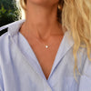 Woman wearing a 14k yellow gold cable chain necklace featuring one 1/4” flat disc engraved with the letter L