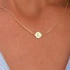 Woman with a 14k yellow gold cable chain necklace featuring one 1/4” flat disc engraved with the letter L
