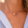 Woman with a 14k yellow gold cable chain necklace featuring one 1/4” flat disc engraved with the letter M