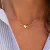 Woman with a 14k yellow gold cable chain necklace featuring one 1/4” flat disc engraved with the letter N