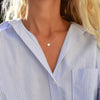 Woman wearing a 14k yellow gold cable chain necklace featuring one 1/4” flat disc engraved with the letter O