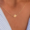 Woman with a 14k yellow gold cable chain necklace featuring one 1/4” flat disc engraved with the letter O
