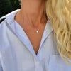 Woman wearing a 14k yellow gold cable chain necklace featuring one 1/4” flat disc engraved with the letter Q