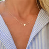 Woman with a 14k yellow gold cable chain necklace featuring one 1/4” flat disc engraved with the letter Q
