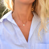 Woman wearing a 14k yellow gold cable chain necklace featuring one 1/4” flat disc engraved with the letter R