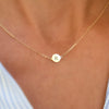 Woman with a 14k yellow gold cable chain necklace featuring one 1/4” flat disc engraved with the letter R