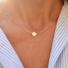 Woman with a 14k yellow gold cable chain necklace featuring one 1/4” flat disc engraved with the letter S