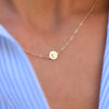 Woman with a 14k yellow gold cable chain necklace featuring one 1/4” flat disc engraved with the letter U