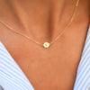 Woman with a 14k yellow gold cable chain necklace featuring one 1/4” flat disc engraved with the letter V