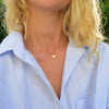 Woman wearing a 14k yellow gold cable chain necklace featuring one 1/4” flat disc engraved with the letter W