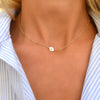 Woman with a 14k yellow gold cable chain necklace featuring one 1/4” flat disc engraved with the letter W