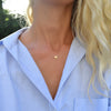 Woman wearing a 14k yellow gold cable chain necklace featuring one 1/4” flat disc engraved with the letter X