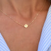 Woman with a 14k yellow gold cable chain necklace featuring one 1/4” flat disc engraved with the letter Y