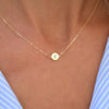 Woman with a 14k yellow gold cable chain necklace featuring one 1/4” flat disc engraved with the letter Z