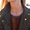 Woman with a Newport necklace featuring one 1/2” cutout Peace Sign and 4 mm gemstones bezel set in 14k yellow gold