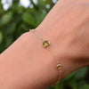 Woman with a Grand & Classic bracelet featuring one 6 mm and four 4 mm briolette Peridots bezel set in 14k yellow gold