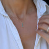 Woman wearing a Providence Alexandrite vertical bar pendant featuring 3 petite baguette stones set in 14k yellow gold