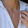 Woman wearing a Providence vertical bar pendant featuring 6 petite White Topaz baguette stones set in 14k yellow gold