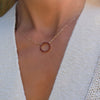 Woman wearing a Rosecliff open circle necklace with sixteen 2 mm faceted round cut garnets prong set in 14k yellow gold