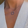 Woman with a Rosecliff open circle necklace with sixteen 2 mm faceted round cut sapphires prong set in 14k yellow gold