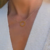 Woman with a Rosecliff open circle necklace with sixteen 2 mm faceted round cut citrines prong set in 14k yellow gold