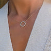 Woman wearing a Rosecliff open circle necklace with 16 alternating 2 mm Nantucket blue topaz & diamonds prong set in 14k gold