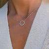 Woman with a Rosecliff open circle necklace with sixteen 2 mm faceted round cut Nantucket blue topaz prong set in 14k gold