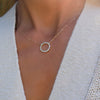 Woman with a Rosecliff open circle necklace with sixteen alternating 2 mm aquamarines & diamonds prong set in 14k gold