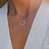 Woman wearing a Rosecliff open circle necklace with sixteen 2 mm faceted round cut aquamarines prong set in 14k yellow gold