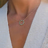 Woman wearing a Rosecliff open circle necklace with 16 alternating 2 mm round cut emeralds & diamonds prong set in 14k gold