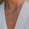 Woman wearing a Rosecliff open circle necklace with sixteen 2 mm faceted round cut emeralds prong set in 14k yellow gold